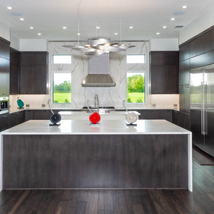 Esempio di una cucina design con ante lisce, ante in legno bruno, paraspruzzi bianco, paraspruzzi in lastra di pietra, elettrodomestici in acciaio inossidabile, parquet scuro, 2 o più isole, pavimento marrone e top bianco