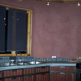 Mid-sized eclectic eat-in kitchen remodeling - Mid-sized eclectic slate floor eat-in kitchen photo in Albuquerque with a triple-bowl sink, recessed-panel cabinets, red cabinets, concrete countertops, gray backsplash, stone tile backsplash, stainless steel appliances and no island