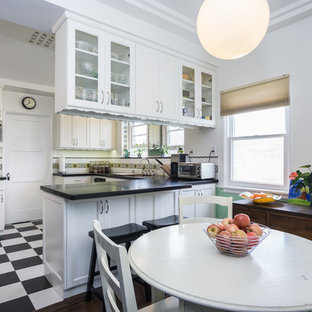 Inspiration for a mid-sized traditional u-shaped eat-in kitchen in Los Angeles with an undermount sink, white cabinets, quartz benchtops, multi-coloured splashback, ceramic splashback, stainless steel appliances, vinyl floors, a peninsula and glass-front cabinets.