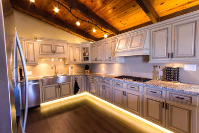 Example of a large transitional u-shaped dark wood floor kitchen design in Miami with a farmhouse sink, raised-panel cabinets, white cabinets, granite countertops and stainless steel appliances
