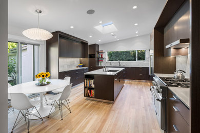 Example of a large trendy u-shaped light wood floor kitchen design in Los Angeles with dark wood cabinets, stainless steel appliances and an island