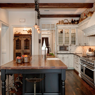 Foto di una cucina country con lavello stile country, ante con bugna sagomata, ante nere, top in legno, paraspruzzi rosso, paraspruzzi in mattoni, elettrodomestici in acciaio inossidabile, pavimento in legno massello medio, pavimento marrone e top marrone