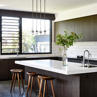 Idées déco pour une très grand cuisine contemporaine en L avec un évier encastré, des portes de placard en bois sombre, un plan de travail en quartz modifié, une crédence blanche, un électroménager en acier inoxydable, un îlot central et une crédence en carrelage métro.