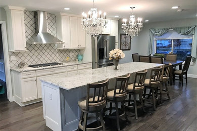 Eat-in kitchen - mid-sized traditional l-shaped medium tone wood floor and gray floor eat-in kitchen idea in Newark with an undermount sink, shaker cabinets, white cabinets, granite countertops, white backsplash, porcelain backsplash, stainless steel appliances, an island and gray countertops