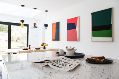 This is an example of a medium sized modern galley open plan kitchen in London with a submerged sink, flat-panel cabinets, white cabinets, terrazzo worktops, white splashback, stainless steel appliances, concrete flooring, an island, grey floors and white worktops.