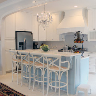 Design ideas for a mid-sized shabby-chic style l-shaped open plan kitchen in Raleigh with a double-bowl sink, raised-panel cabinets, white cabinets, quartzite benchtops, white splashback, glass tile splashback, stainless steel appliances, with island and brick floors.