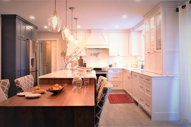 Example of a large classic l-shaped porcelain tile and gray floor eat-in kitchen design in Ottawa with a farmhouse sink, shaker cabinets, white cabinets, solid surface countertops, white backsplash, subway tile backsplash, stainless steel appliances, an island and multicolored countertops