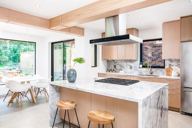 Inspiration for a large contemporary l-shaped porcelain tile and beige floor eat-in kitchen remodel in Toronto with an undermount sink, flat-panel cabinets, light wood cabinets, marble countertops, white backsplash, stone slab backsplash, stainless steel appliances, an island and white countertops
