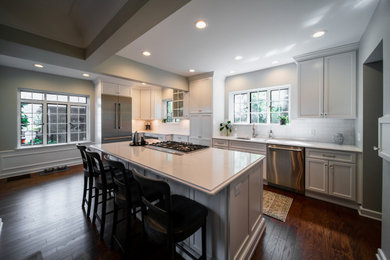 Eat-in kitchen - large traditional l-shaped medium tone wood floor and brown floor eat-in kitchen idea in Other with a single-bowl sink, flat-panel cabinets, white cabinets, quartz countertops, white backsplash, ceramic backsplash, stainless steel appliances, an island and white countertops