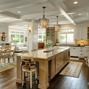 Ispirazione per un'ampia cucina tradizionale con lavello stile country, ante bianche, top in granito, paraspruzzi beige, elettrodomestici in acciaio inossidabile, parquet scuro, ante con riquadro incassato, pavimento marrone e top beige