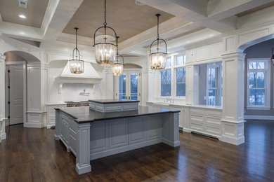 Large transitional u-shaped dark wood floor and brown floor open concept kitchen photo in Columbus with a farmhouse sink, beaded inset cabinets, white cabinets, solid surface countertops, white backsplash, subway tile backsplash, stainless steel appliances and an island