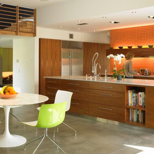 Foto di una cucina moderna con lavello sottopiano, ante lisce, ante in legno scuro, paraspruzzi arancione, elettrodomestici in acciaio inossidabile e pavimento in cemento