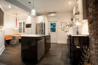 Mittelgroße Moderne Küche mit Unterbauwaschbecken, weißen Schränken, Mineralwerkstoff-Arbeitsplatte, Küchengeräten aus Edelstahl, Schieferboden und Kücheninsel in Montreal