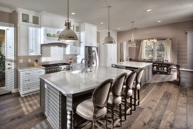 Open concept kitchen - large cottage single-wall medium tone wood floor open concept kitchen idea in Sacramento with shaker cabinets, white cabinets, white backsplash, subway tile backsplash, stainless steel appliances and two islands