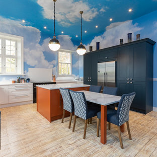 Design ideas for an eclectic u-shaped kitchen in Other with a belfast sink, shaker cabinets, white cabinets, stainless steel appliances, medium hardwood flooring, an island, brown floors and white worktops.