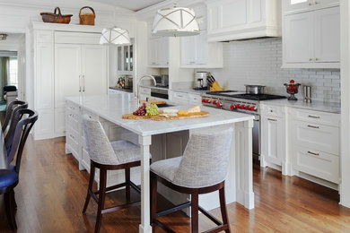 Inspiration for a large transitional u-shaped dark wood floor and brown floor eat-in kitchen remodel in Chicago with an undermount sink, recessed-panel cabinets, white cabinets, marble countertops, white backsplash, subway tile backsplash, stainless steel appliances, an island and white countertops
