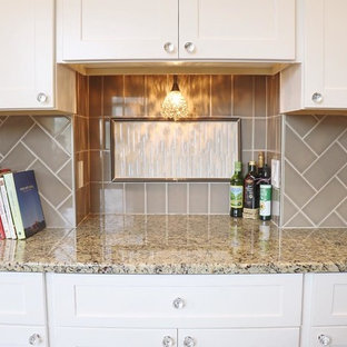 This is an example of a small traditional galley eat-in kitchen in New York with an undermount sink, shaker cabinets, white cabinets, granite benchtops, grey splashback, glass tile splashback, medium hardwood floors, a peninsula, stainless steel appliances, grey floor and beige benchtop.