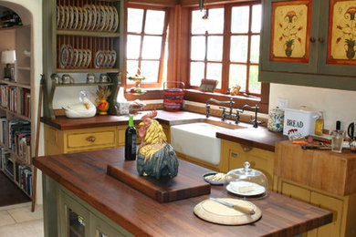 Photo of a medium sized farmhouse u-shaped kitchen/diner in San Francisco with a belfast sink, beaded cabinets, distressed cabinets, wood worktops, integrated appliances, limestone flooring and an island.