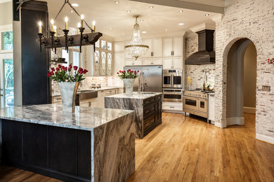 Inspiration for a large timeless light wood floor and brown floor open concept kitchen remodel in Atlanta with a farmhouse sink, flat-panel cabinets, white cabinets, limestone countertops, red backsplash, brick backsplash, stainless steel appliances, two islands and gray countertops