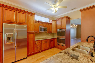 Example of a large classic galley medium tone wood floor eat-in kitchen design in Tampa with an undermount sink, beaded inset cabinets, medium tone wood cabinets, granite countertops, beige backsplash, ceramic backsplash, stainless steel appliances and an island