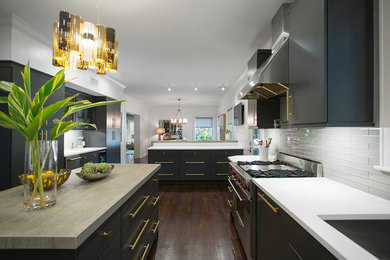 Inspiration for a large contemporary l-shaped dark wood floor and brown floor eat-in kitchen remodel in Austin with a double-bowl sink, flat-panel cabinets, black cabinets, quartz countertops, gray backsplash, glass tile backsplash, stainless steel appliances and an island