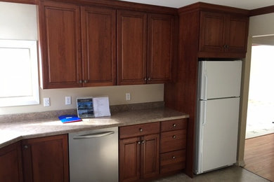 This is an example of a medium sized classic l-shaped kitchen/diner in Cedar Rapids with a submerged sink, raised-panel cabinets, medium wood cabinets, laminate countertops, beige splashback, laminate floors, no island and beige floors.