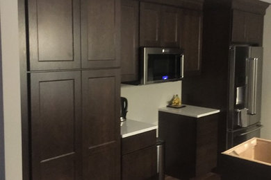 Foto på ett mellanstort funkis kök, med en undermonterad diskho, luckor med infälld panel, vita skåp, bänkskiva i kvartsit, rostfria vitvaror och en köksö