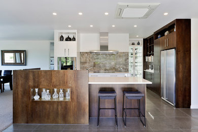 This is an example of a medium sized traditional galley open plan kitchen in Other with a submerged sink, flat-panel cabinets, dark wood cabinets, engineered stone countertops, grey splashback, stainless steel appliances, porcelain flooring, an island, grey floors and white worktops.
