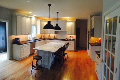 Inspiration for a large transitional u-shaped medium tone wood floor and brown floor eat-in kitchen remodel in Philadelphia with shaker cabinets, an island, white cabinets, an undermount sink, white backsplash, subway tile backsplash, stainless steel appliances, quartzite countertops and black countertops