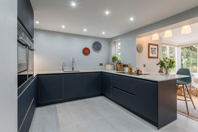 This is an example of a medium sized contemporary u-shaped kitchen/diner in Cheshire with glass-front cabinets, blue cabinets and black appliances.