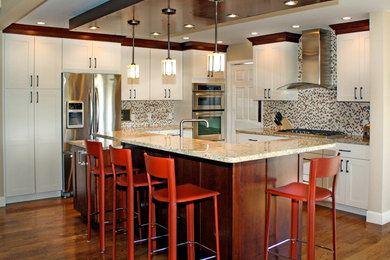 Exempel på ett klassiskt kök, med en undermonterad diskho, skåp i shakerstil, vita skåp, granitbänkskiva, flerfärgad stänkskydd, stänkskydd i stenkakel, rostfria vitvaror, mellanmörkt trägolv och en köksö