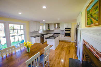 Inspiration for a mid-sized contemporary u-shaped medium tone wood floor eat-in kitchen remodel in Philadelphia with a double-bowl sink, recessed-panel cabinets, white cabinets, granite countertops, white backsplash, subway tile backsplash, stainless steel appliances and an island