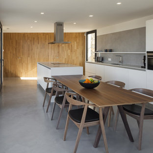 Imagen de cocina comedor de galera y de microcemento, contemporánea, grande, con suelo de cemento, fregadero bajoencimera, armarios con paneles lisos, puertas de armario blancas, encimera de acrílico, salpicadero verde, electrodomésticos de acero inoxidable, una isla y microcemento