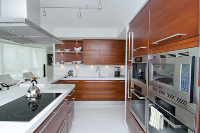 Mid-sized minimalist galley porcelain tile and white floor eat-in kitchen photo in Miami with flat-panel cabinets, medium tone wood cabinets, quartz countertops, white backsplash and an island