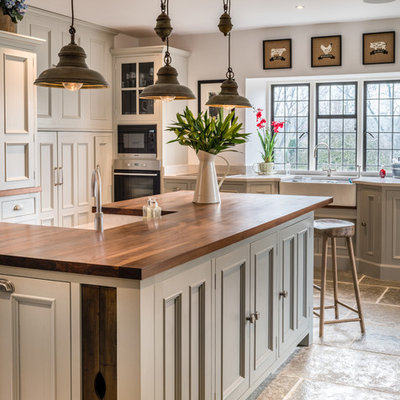 Example of a farmhouse kitchen design in Other with a farmhouse sink, beaded inset cabinets, gray cabinets, wood countertops, stainless steel appliances, an island and brown countertops