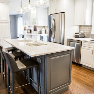 Mid-sized transitional eat-in kitchen inspiration - Eat-in kitchen - mid-sized transitional l-shaped medium tone wood floor and brown floor eat-in kitchen idea in Chicago with an undermount sink, raised-panel cabinets, white cabinets, quartz countertops, gray backsplash, ceramic backsplash, stainless steel appliances, an island and white countertops