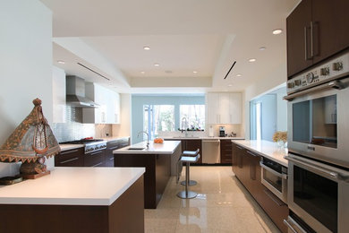 This is an example of a large modern u-shaped enclosed kitchen in Houston with a submerged sink, flat-panel cabinets, dark wood cabinets, stainless steel appliances, an island, engineered stone countertops, grey splashback, ceramic splashback, laminate floors and beige floors.
