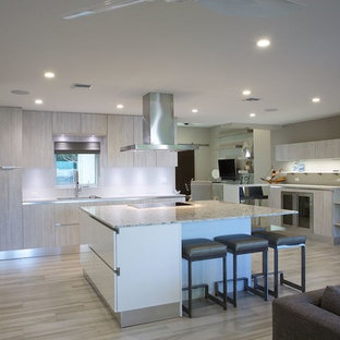 Photo of a mid-sized tropical eat-in kitchen in Miami with a single-bowl sink, flat-panel cabinets, light wood cabinets, quartz benchtops, stainless steel appliances, porcelain floors and with island.