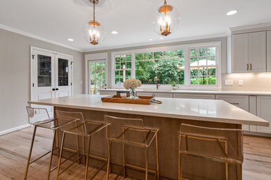 Transitional light wood floor and brown floor eat-in kitchen photo in Atlanta with an undermount sink, shaker cabinets, white cabinets, quartz countertops, gray backsplash, ceramic backsplash, stainless steel appliances, an island and white countertops