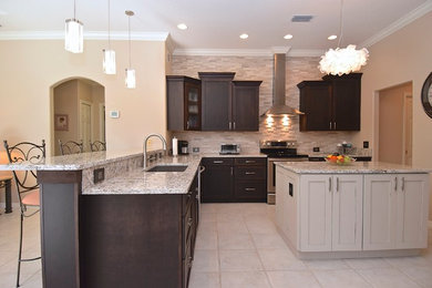 Large elegant l-shaped ceramic tile and white floor open concept kitchen photo in Tampa with dark wood cabinets, granite countertops, gray backsplash, stone tile backsplash, stainless steel appliances, an island, an undermount sink and shaker cabinets