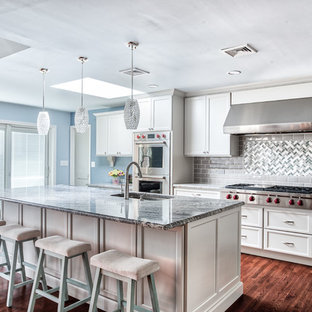 Large transitional kitchen pictures - Inspiration for a large transitional l-shaped medium tone wood floor and brown floor kitchen remodel in New York with an undermount sink, granite countertops, gray backsplash, glass tile backsplash, stainless steel appliances, an island, shaker cabinets and white cabinets