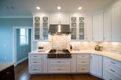 Transitional l-shaped medium tone wood floor eat-in kitchen photo in Boston with white cabinets, granite countertops, gray backsplash, stainless steel appliances and an island