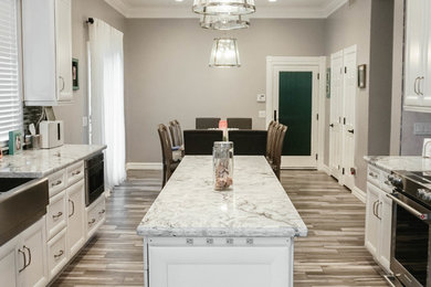 Large minimalist galley porcelain tile and brown floor eat-in kitchen photo in Phoenix with a farmhouse sink, white cabinets, quartzite countertops, gray backsplash, glass tile backsplash, stainless steel appliances, an island and white countertops