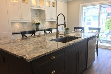Inspiration for a mid-sized contemporary u-shaped laminate floor and gray floor kitchen remodel in Toronto with an undermount sink, shaker cabinets, white cabinets, granite countertops, gray backsplash, marble backsplash, stainless steel appliances, an island and white countertops