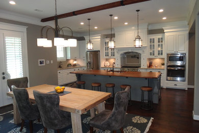 Inspiration for a large timeless l-shaped dark wood floor open concept kitchen remodel in Houston with a double-bowl sink, raised-panel cabinets, white cabinets, granite countertops, beige backsplash, stainless steel appliances, an island and subway tile backsplash