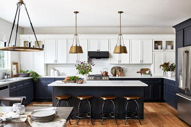 Inspiration for a large farmhouse u-shaped medium tone wood floor and brown floor open concept kitchen remodel in Austin with an undermount sink, shaker cabinets, blue cabinets, quartz countertops, white backsplash, ceramic backsplash, stainless steel appliances, an island and white countertops