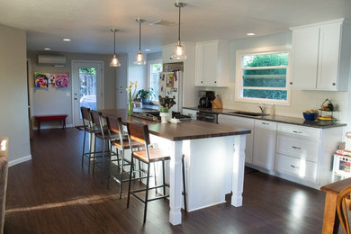 Example of a mid-sized transitional galley dark wood floor and brown floor open concept kitchen design in Other with an undermount sink, shaker cabinets, white cabinets, wood countertops, white backsplash, porcelain backsplash, white appliances and an island