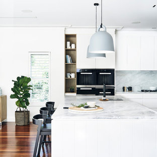 Design ideas for a large scandinavian l-shaped open plan kitchen in Sydney with flat-panel cabinets, white cabinets, marble benchtops, white splashback, stone slab splashback, stainless steel appliances, medium hardwood floors, with island and brown floor.