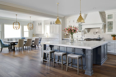 Inspiration for a mid-sized transitional galley medium tone wood floor and multicolored floor eat-in kitchen remodel in Los Angeles with white cabinets, solid surface countertops, white backsplash, marble backsplash, stainless steel appliances, an island, white countertops and recessed-panel cabinets