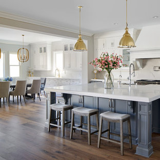 Inspiration for a mid-sized transitional galley eat-in kitchen in Los Angeles with white cabinets, solid surface benchtops, white splashback, marble splashback, stainless steel appliances, medium hardwood floors, with island, multi-coloured floor, white benchtop and recessed-panel cabinets.